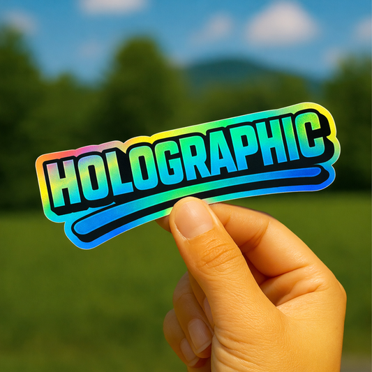 Hand holding a holographic 'HOLOGRAPHIC' sticker with a blurred natural background